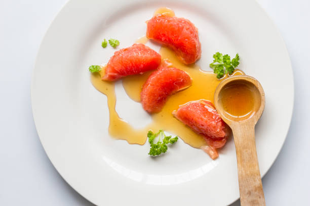 istock Grapefruit segments with honey dribbled  - Blood orange healthy salad on white background 1403818793