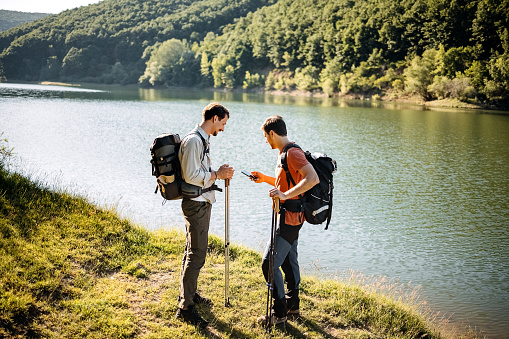 Two male friends hiking in nature by the lake