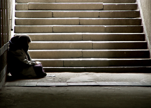 photo of beggar woman reading the book in undergrund subway