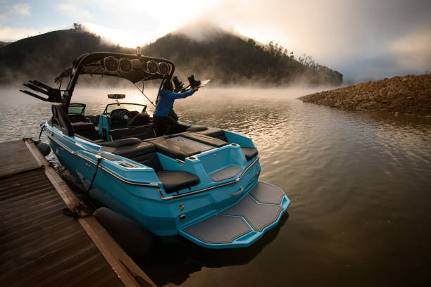 barca moderna blu brillante ormeggiata al molo e un uomo su di essa - wakeboarding foto e immagini stock