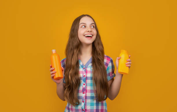 istock amazed child with shampoo bottle on yellow background 1403826060