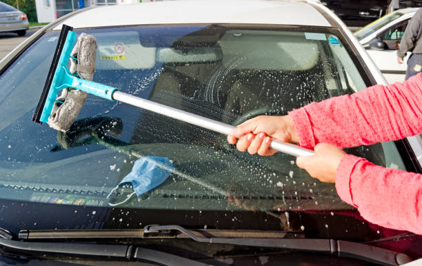 istock Woman washing car windshield with squeegee and soapy sponge 1403826372