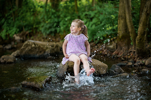 Happy little girl enjoying in the waterfall
