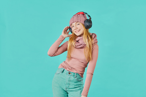 Beautiful young woman listening to music using headphones smiling looking to the side