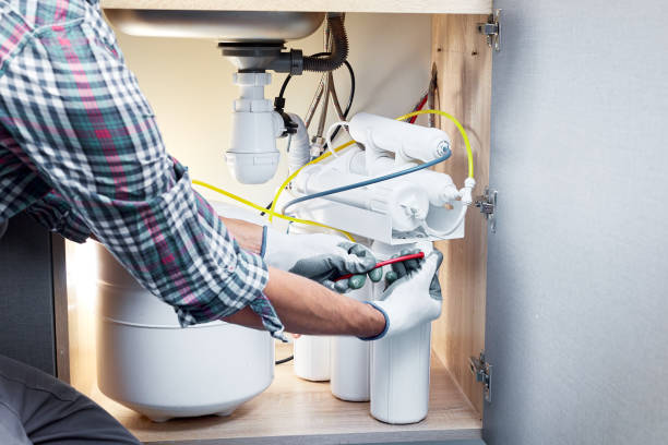 Technician installing or repairing system of water filtration. Plumber hand in gloves replace water filter cartridges at home kitchen.