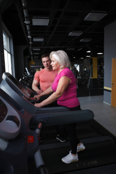 istock Senior woman exercising with personal trainer at gym 1403831507