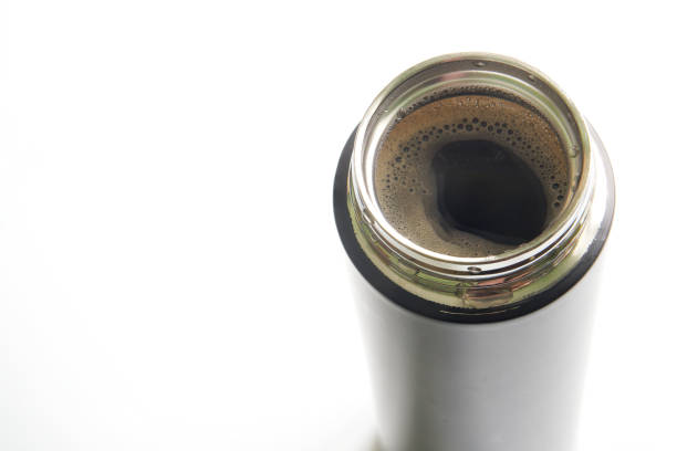An open metal thermo mug or a small thermos with hot coffee. White background. View from above. Copy space for an inscription. Selective focus. Close-up