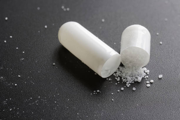 istock Opened medical pill capsule with white powder on a textured black background. Macro. Selective focus 1403833082