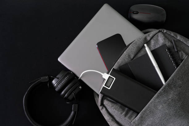 istock Silver laptop and modern gadgets lie in a gray backpack on a dark table. Travel, trip, study and lifestyle with modern computer technology. 1403833107