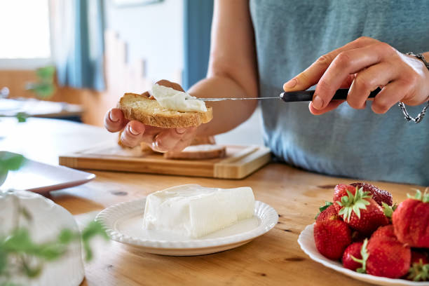 woman making summer strawberry sandwich. female hands spread stracchino cheese on bread for toast. healthy eating, fruit dieting brunch. - bruschetta buffet party food imagens e fotografias de stock