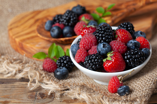 Fresh berries in a bowl on rustic wooden background