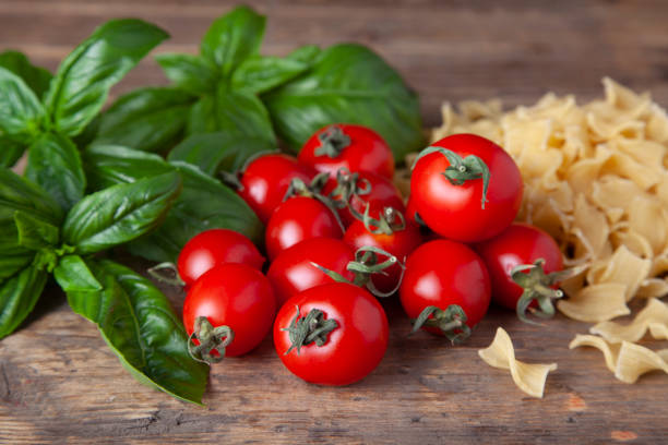 Pasta with cherry tomato, basil and garlic on rustic wooden background