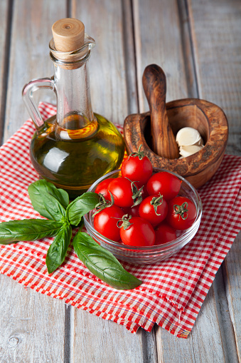Cherry tomato, basil, olive oil and garlic on rustic wooden background