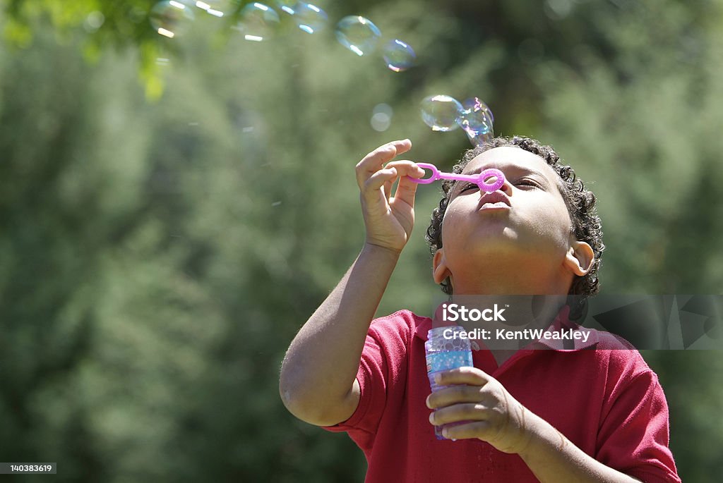 Chłopiec wieje pęcherzyki powietrza w park - Zbiór zdjęć royalty-free (Pałeczka do baniek mydlanych)