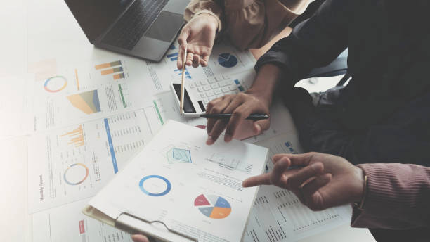 istock Business People Meeting using laptop computer, calculator,notebook,stock market chart paper for analysis Plans to improve quality next month. Conference Discussion Corporate Concept 1403837165