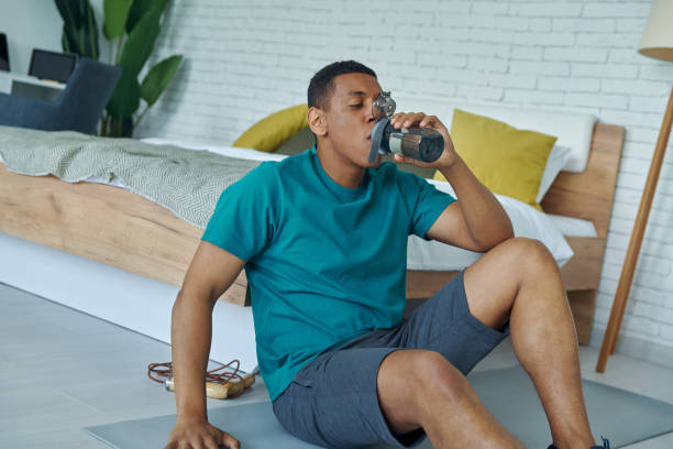 istock Young multiracial man enjoying fresh water after training at home 1403839075