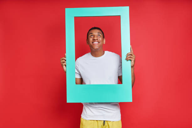 istock Cheerful mixed race man looking through a picture frame 1403839105