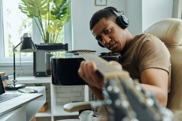 istock Concentrated young mixed race man examining acoustic guitar 1403839155