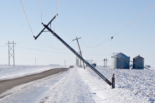 Power lines weighed down by ice cause damage along a country road. 