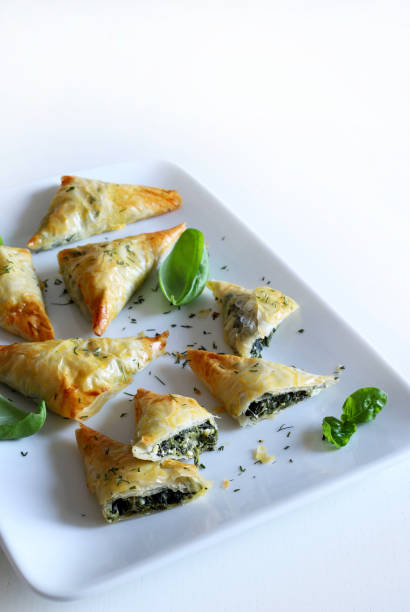 Spanakopita, greek spinach pie. Greek food. Spanakopita, phyllo pastry triangle with spinach and feta cheese on white background. Directly above. spanakopita stock pictures, royalty-free photos & images