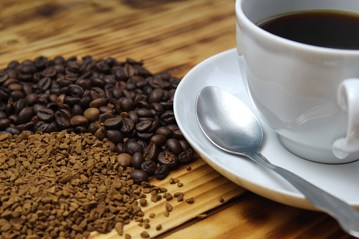 Instant coffee and beans lie on a wooden background.