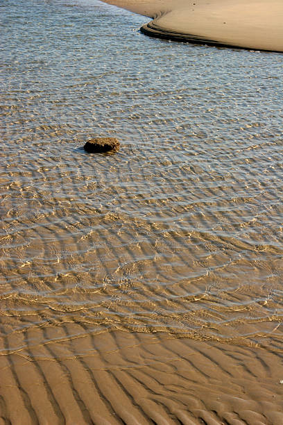 shallow water surrounds single rock in red sea stock photo