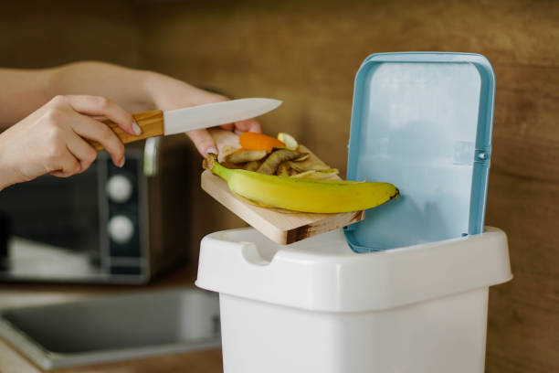 istock Woman throws vegetable cuttings in a compost bucket. Close up. 1403843336