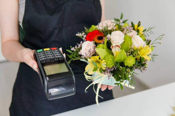 銀行決済端末と花束を手にした若い女性花屋のクローズアップ。中小企業のコンセプト。 - flower shop flower flower market store ストックフォトと画像