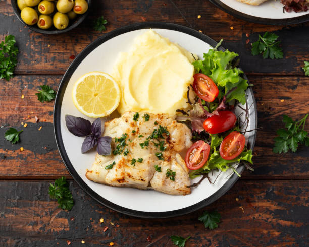istock Fried cod loin fillet with mashed potato and vegetable salad served with fresh lemon 1403844645