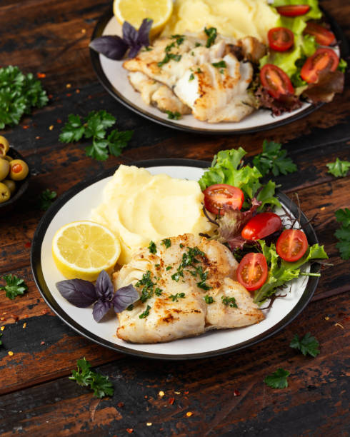 istock Fried cod loin fillet with mashed potato and vegetable salad served with fresh lemon 1403844695