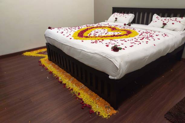 結婚式の夜の部屋のベッド羽毛布団にレイアウトされたバラと花びら - honeymoon romance wedding bedroom ストックフォトと画像
