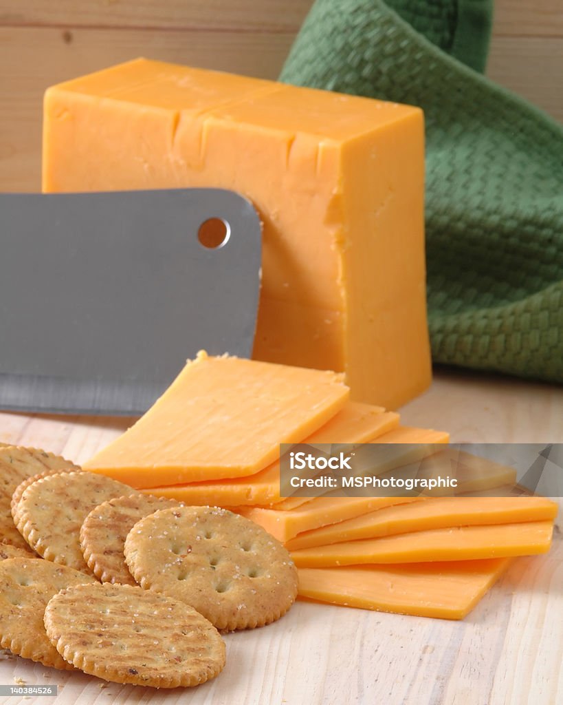 Sliced Cheese A block of sliced cheese with wheat crackers on a cutting board Appetizer Stock Photo