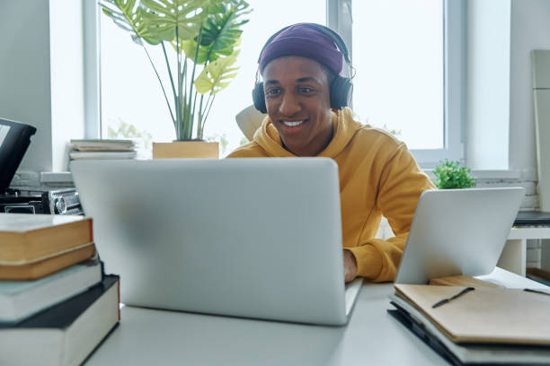 istock Cheerful mixed race man in headphones using laptop 1403846697