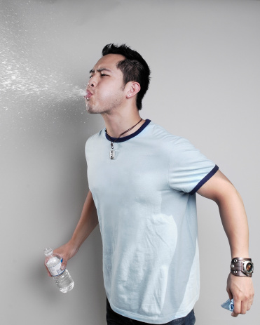 Asian male spitting water from his mouth
