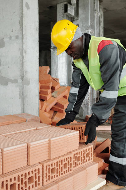 istock Mature experienced black man in workwear bending over stack of bricks 1403846877