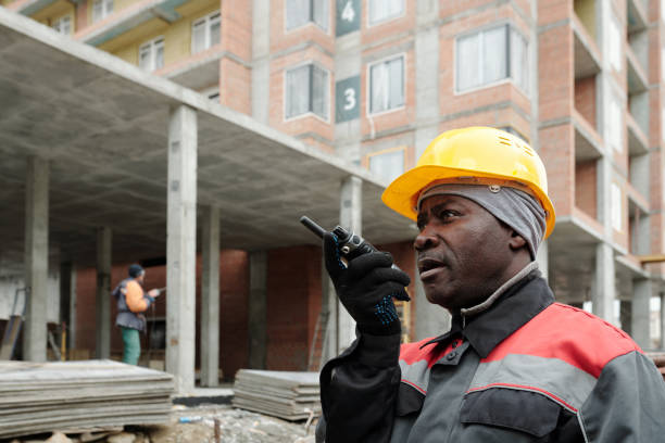 istock Aged builder in hardhat and workwear speaking in walkie-talkie at work 1403846901