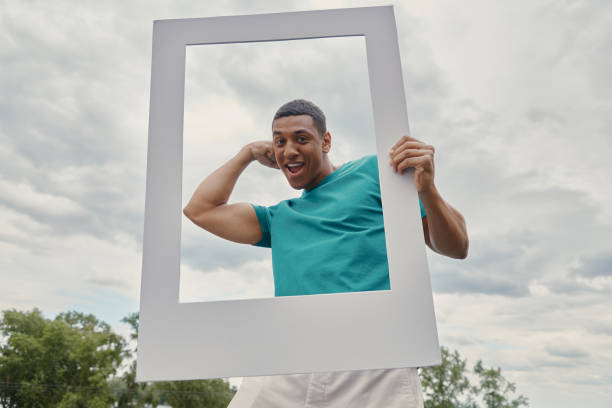 Handsome mixed race man looking through a picture frame and gesturing