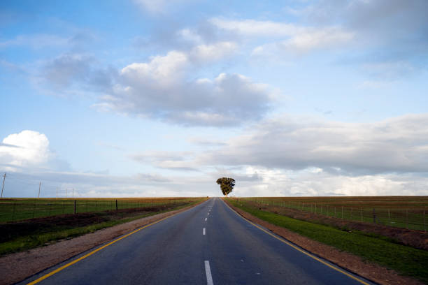 Bend road leading up a hill with blue sky and clouds