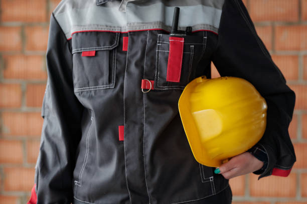 istock Middle section of young modern female builder in uniform holding hardhat 1403847117