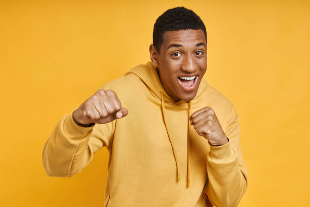 istock Playful mixed race man standing in punching pose against yellow background 1403847358