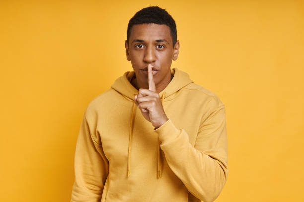 istock Young mixed race man holding finger on lips 1403848070