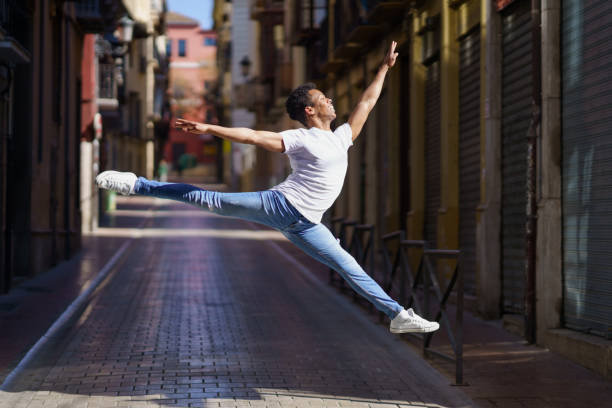 Black athletic man doing an acrobatic jump outdoors. Cuban male.