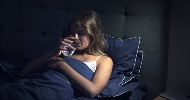 Woman in bed drinking a glass of water stock photo
