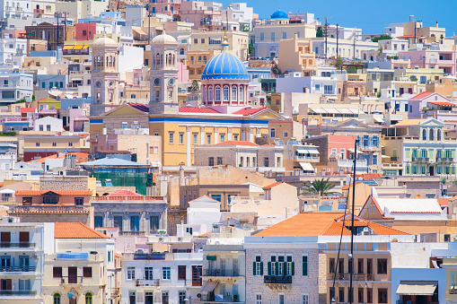 Ermoupolis town, Greece. A town on the side of a mountain. Houses and streets in Greek architecture. Photography for travel and adventure. Cascading arrangement of buildings on the hillside.