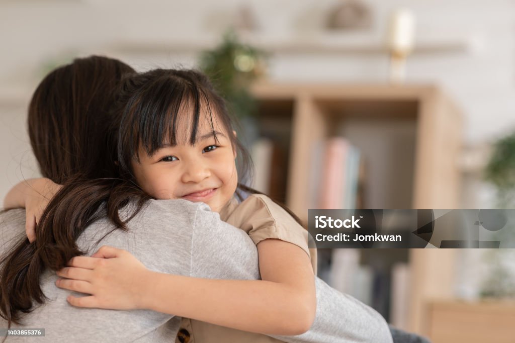 An Asian girl hugs her mom from the front and she also smile. kids feels so happy with their moment that they spent together. A strong mind could built up from a strong family.Happiness Family Concept Life Insurance Stock Photo