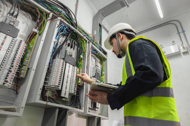 electrical engineer team working front control panel, an electrical engineer is installing and using a tablet to monitor the operation of an electrical control panel in a factory service room. - elektriker bildbanksfoton och bilder