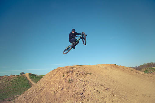 jumping a huge jump with the downhill mountain bike, tabletop style with full safety gear.