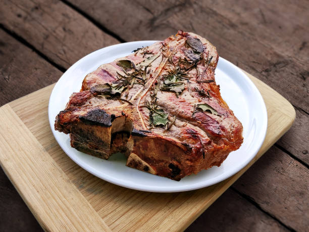White round plate with Whole grilled T-bone steak isolated on rustic wood