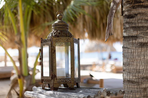 Vintage lantern with candle on a wooden table at beach club. Atmospheric mood.