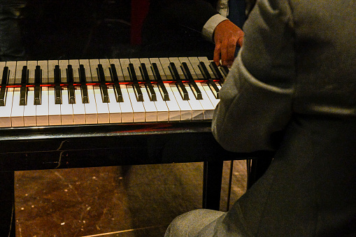 Hands of a concert performer playing the keyboard of a piano at a concert.